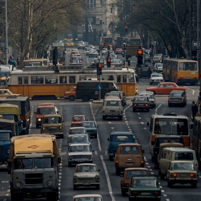 AI-restored archival footage of heavy traffic, trams and buses on a busy Budapest street.